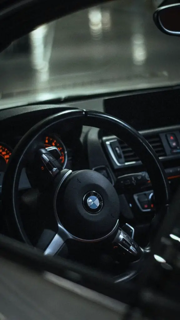 A close-up of a BMW dashboard with the check engine light illuminated, signaling a potential engine issue that needs diagnosis.